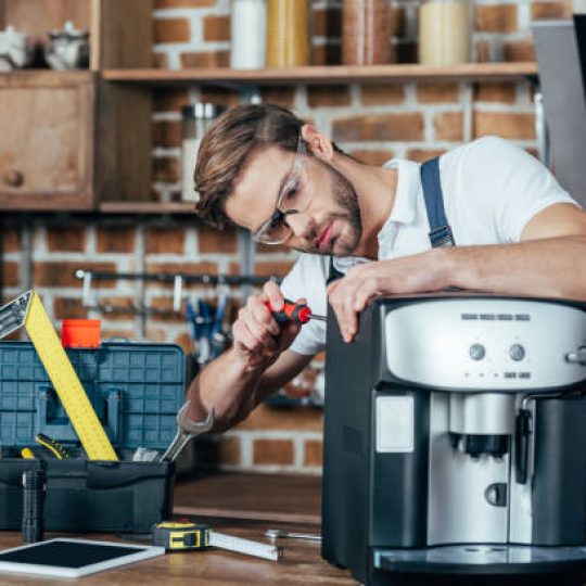professional young repairman in eyeglasses fixing coffee machine
